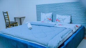 A neatly made bed with floral pillows and a blue headboard. - Peaceful apartment with WiFi in charming Musanze-down town. (Musanze)