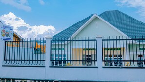A building with a white facade, a green roof, and a black metal fence. - Peaceful apartment with WiFi in charming Musanze-down town. (Musanze)