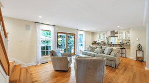 Un salón amplio con un sofá grande, dos sillones y una zona de comedor con una cocina al fondo.