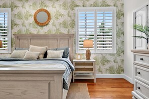 A bedroom with a bed, nightstand, dresser, and a window with shutters. - Sweet "Rae" of Sunshine-Coastal Oasis, Prime location & GOLF CART INCLUDED! (Siesta Key)