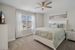 A bedroom with a bed, nightstands, a ceiling fan, and a window with blinds.