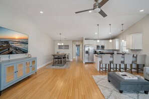 A modern kitchen with white cabinets, stainless steel appliances, and a dining area with a wooden table and chairs.