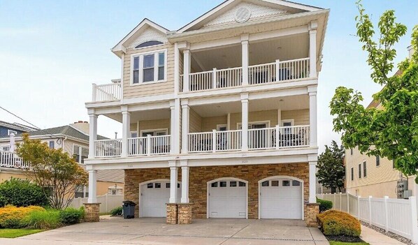 Une maison à deux étages avec un balcon au deuxième étage, un garage et une véranda à l’avant.