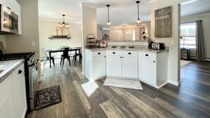 Une cuisine moderne avec des meubles blancs, un îlot central et des luminaires suspendus.