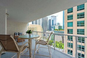 A balcony with a round table and two chairs, a potted plant, and a view of tall buildings. - Grand 1BR | Free Parking | Near Bayfront Park (Miami)