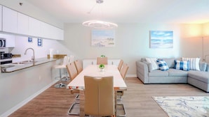 A modern living space with a dining area, kitchen, and seating area.
