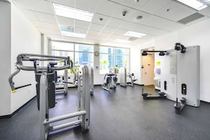 Une salle de sport équipée de divers appareils d’exercice, dotée de grandes fenêtres et présentant un design moderne et épuré.