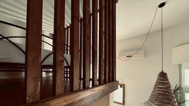 Una scala in legno con un lampadario intrecciato a sospensione.