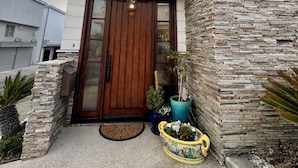 A modern two-story house with a wooden front door, stone facade, and a balcony.