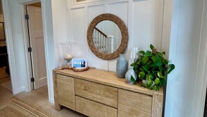 A wooden console table with a mirror, a vase, and a plant.