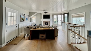 A spacious living area with a fireplace, wooden flooring, and a view of the outside.
