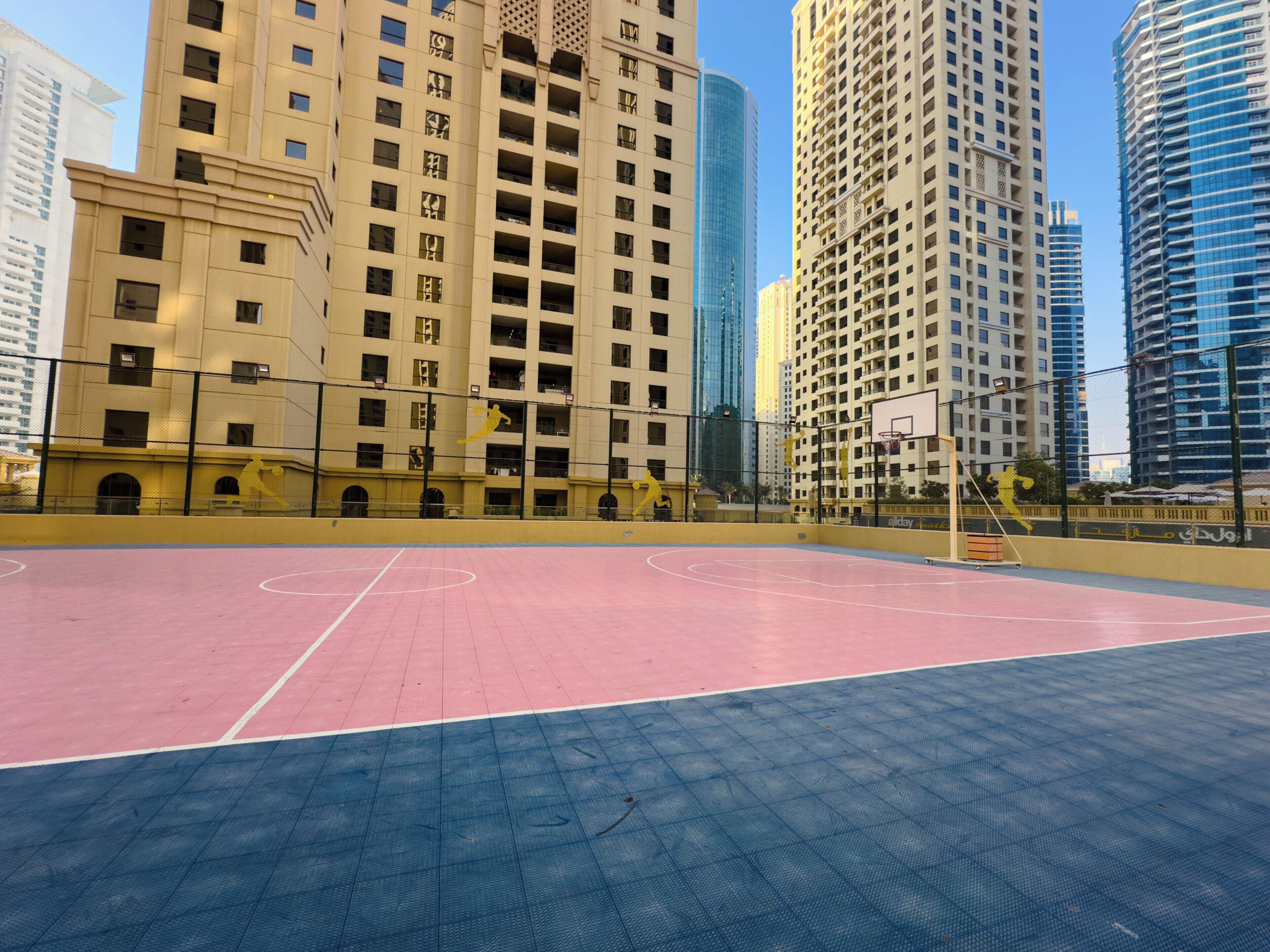 Ein Basketballplatz im Freien, umgeben von Hochhäusern.