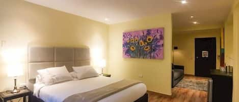 A hotel room with a bed, bedside tables, a painting, a desk, and a chair.