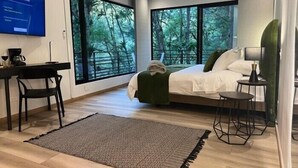 Ein modernes Hotelzimmer mit einem großen Bett, einem Schreibtisch mit Stuhl, einem kleinen Tisch und einem Fernseher.