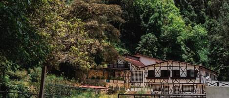 A traditional building with a balcony overlooking a garden and a pool area.