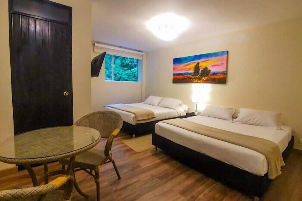 Una habitación con dos camas individuales, una mesa redonda de vidrio y una silla.