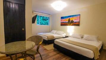 Una habitación con dos camas individuales, una mesa redonda de vidrio y una silla.