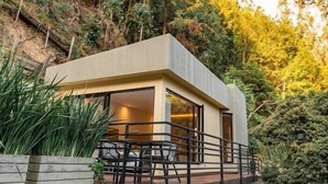 Ein modernes Haus mit flachem Dach, großen Fenstern und einem Balkon mit Geländer.