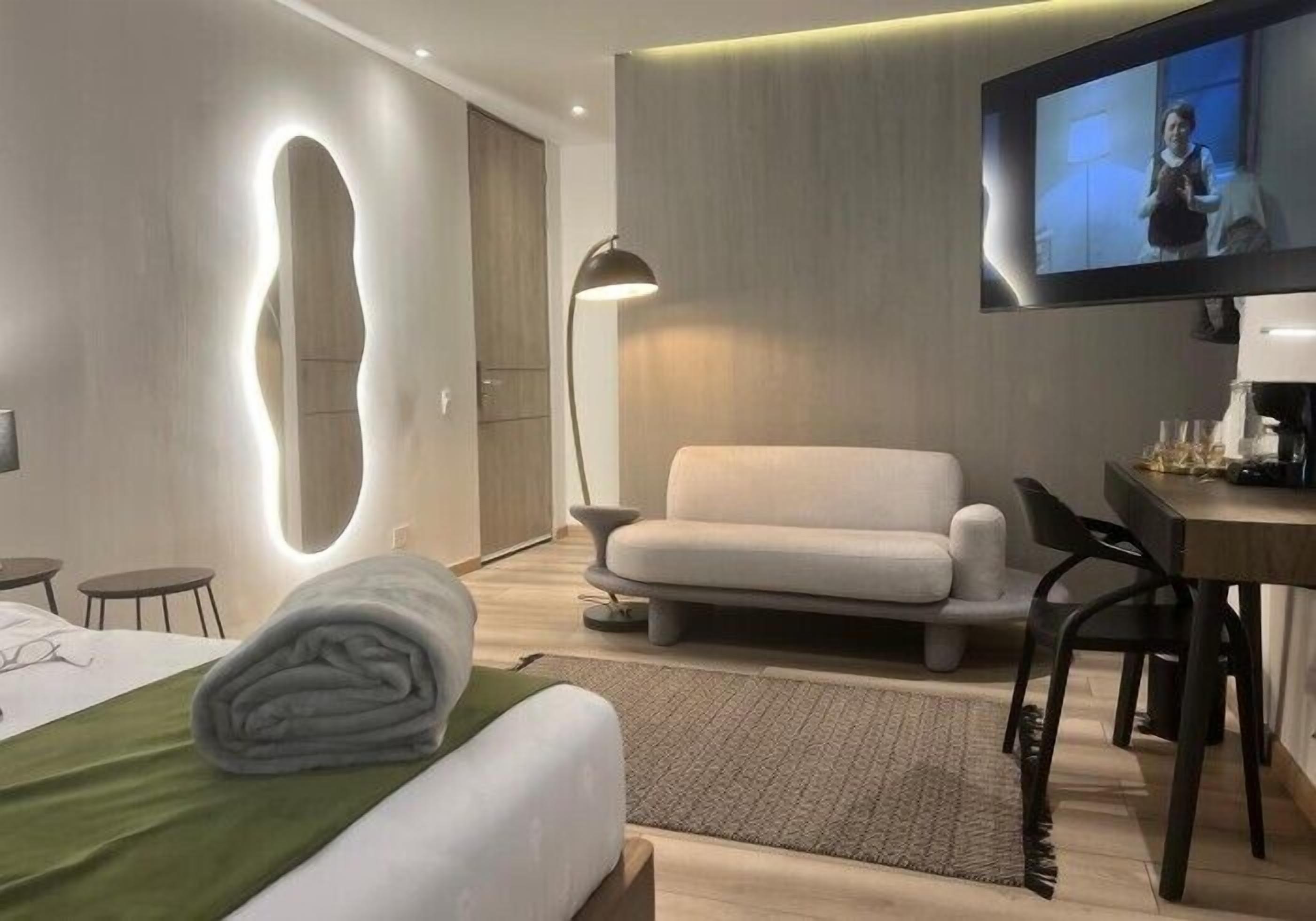 Una habitación de hotel moderna con cama, sofá, escritorio y televisión.