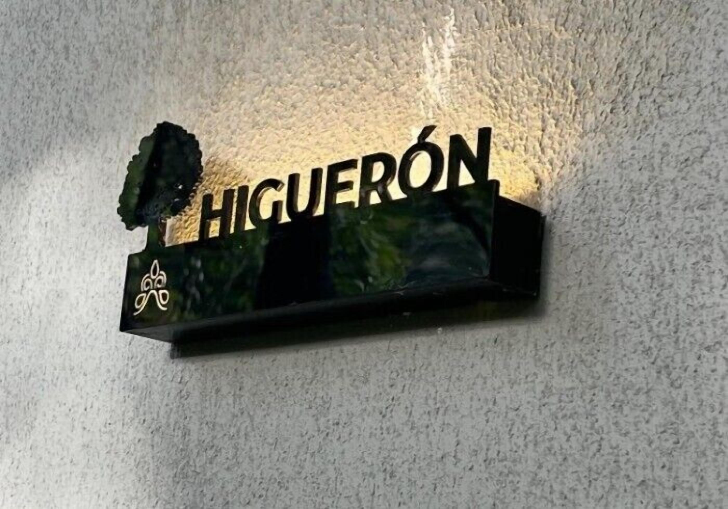 A sign with the name "HIGUERÓN" on a textured wall.