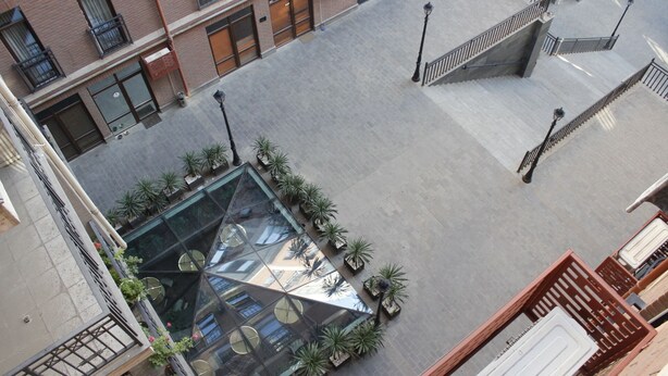 Ein Innenhof mit Glasdach, Blumentöpfen und einer Treppe.
