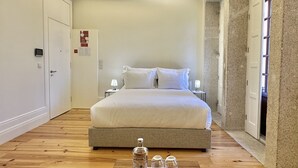 Ein modernes Hotelzimmer mit einem großen Bett, Nachttischen, einer Minibar und Blick nach außen.