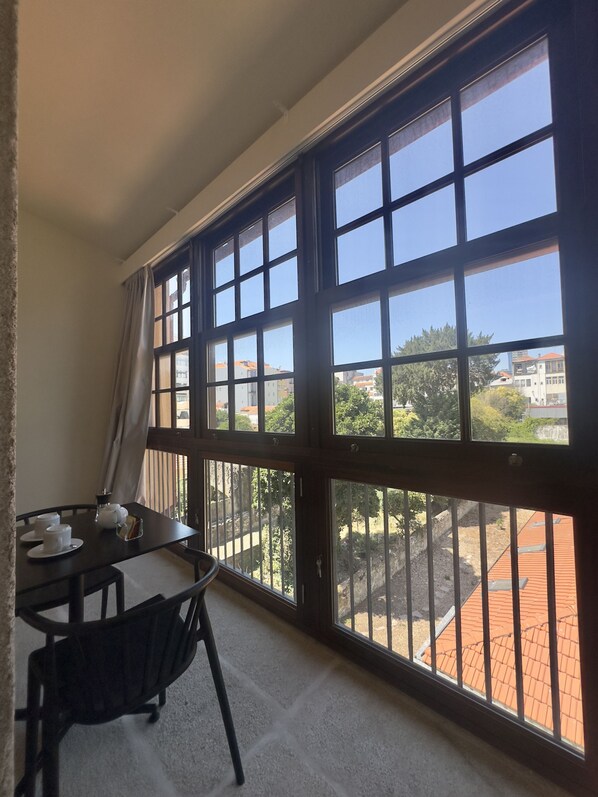 A room with a large window, a table with cups and a tray, and a chair.