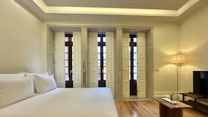 A bedroom with a large bed, wooden flooring, a TV, and a lamp. - Collection 4T in Oporto (Porto)