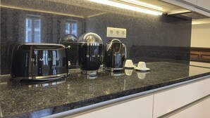 A modern kitchen with a granite countertop, a black toaster, a coffee maker, and a kettle. - Collection 3F in Oporto (Porto)