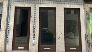 A building with three ground-floor doors, a balcony with metal railings, and a patterned tile facade. - Collection 3F in Oporto (Porto)