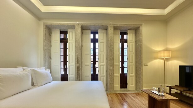 A bedroom with a large bed, wooden flooring, a TV, and a lamp. - Collection 4F in Oporto (Porto)