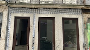 A building with three ground-floor doors, a balcony with ornate metal railings, and a patterned tile facade. - Collection 4F in Oporto (Porto)