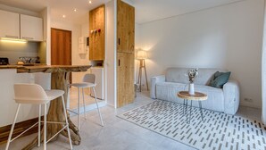 A modern kitchen with white cabinets, a wooden island, and a dining area with white chairs.