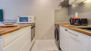 A compact kitchen with a microwave, toaster, and washing machine.