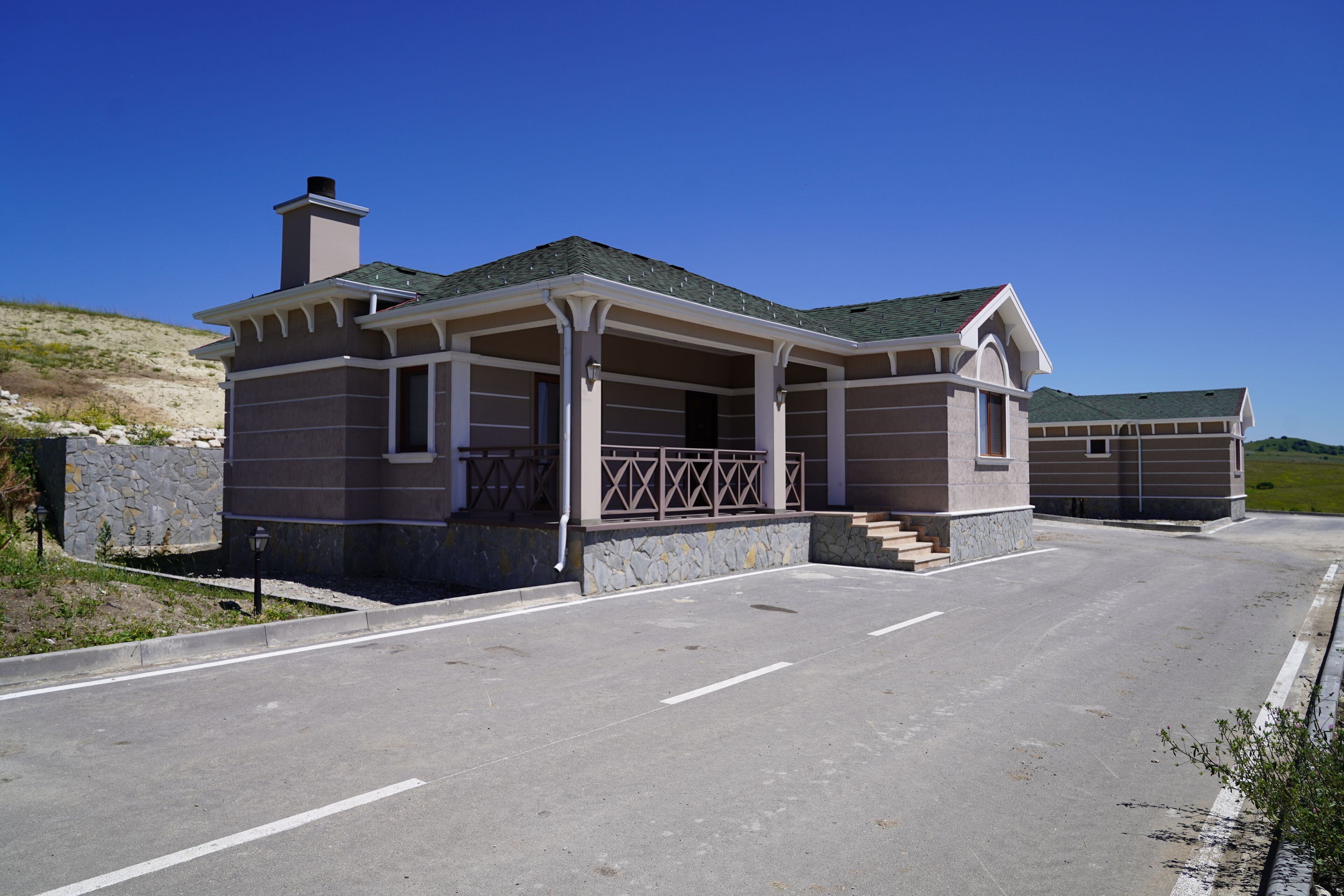 Una casa a due piani con facciata in pietra, un portico con ringhiere e un garage.