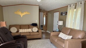 A living room with a brown leather sofa, a recliner, and a patterned rug. - 3-bedroom house in Rexton right on the ATV/snowmobile trails (Naubinway)