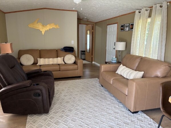 A living room with a brown leather sofa, a recliner, and a patterned rug.