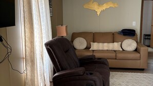 A living room with a brown leather recliner, beige walls, a brown sofa, and a patterned rug. - 3-bedroom house in Rexton right on the ATV/snowmobile trails (Naubinway)