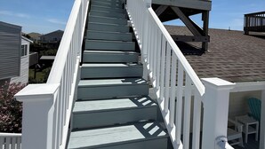 Una escalera de madera con barandas blancas que lleva a una terraza.