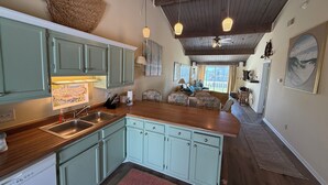 Una cocina con armarios azul claro, encimera de madera y ventilador de techo.