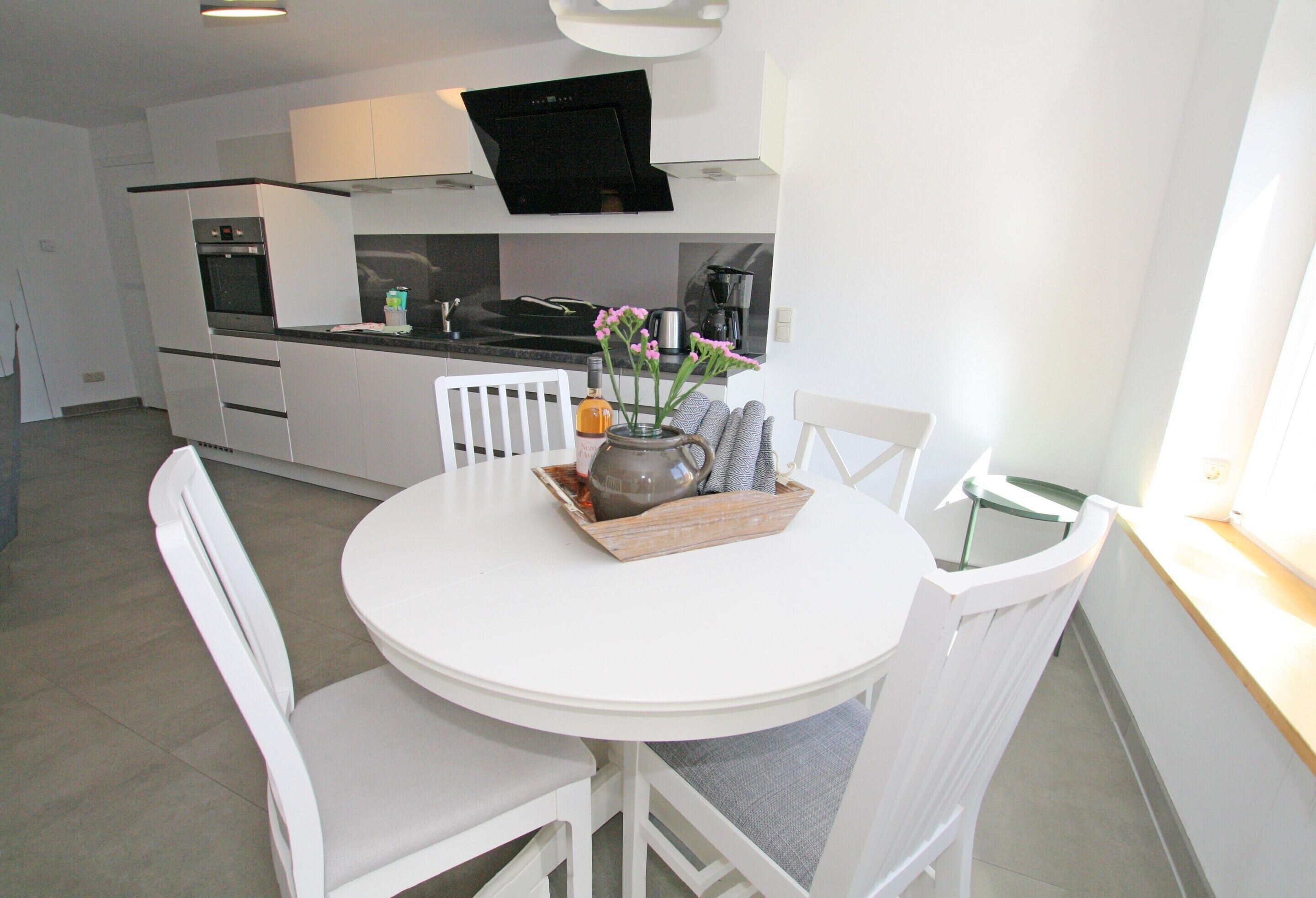 A modern kitchen with white cabinetry, a built-in oven, and a coffee maker.