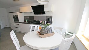 Une cuisine moderne avec des meubles blancs, un four encastré et une machine à café.
