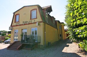 A two-story building with a staircase leading to the entrance, a small balcony, and a sign above the door.