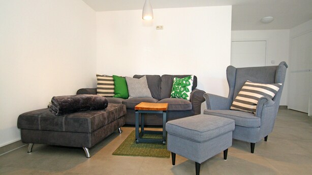 A living room with a grey sofa, a grey armchair, a small ottoman, and a wooden coffee table. - Luxuriose Ferienwohnung mit Terrasse, Wiek (Wiek)