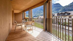 Ein Holzbalkon mit Tisch und Stühlen, mit Blick auf eine gebirgige Landschaft.