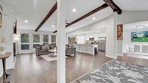 A spacious living area with a kitchen and dining space, featuring a large island, modern appliances, and a view of the outdoors.
