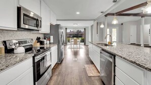 A modern kitchen with white cabinets, stainless steel appliances, and granite countertops.