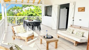 Une vaste terrasse extérieure aménagée avec des meubles en bois, une table à manger et un réfrigérateur.