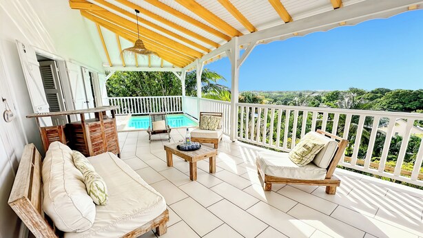 Un espace extérieur abrité, doté d’une piscine, de mobilier en bois et offrant une vue sur le paysage.