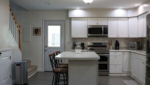 A modern kitchen with white cabinetry, stainless steel appliances, and a central island.